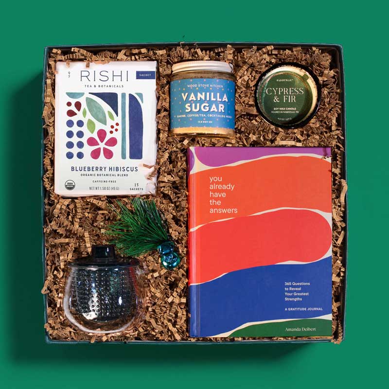 Holiday gift box with herbal tea, a teapot, an inspirational book and vanilla sugar
